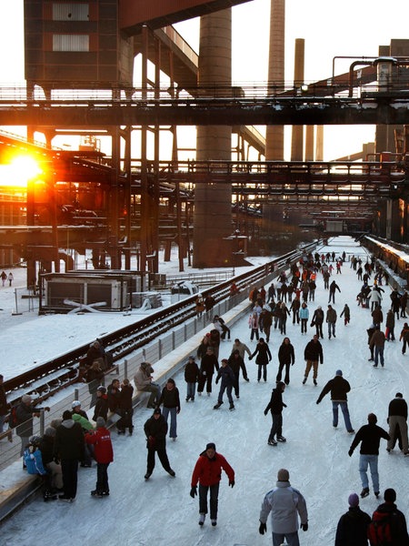 Auf der Eisbahn vor der Zeche Zollverein in Essen fährt eine Gruppe von Besuchern Schlittschuh