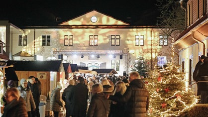 Weihnachtsmarkt in Innenhof von Schloss Benkhausen mit illuminiertem Schloss im Hintergrund