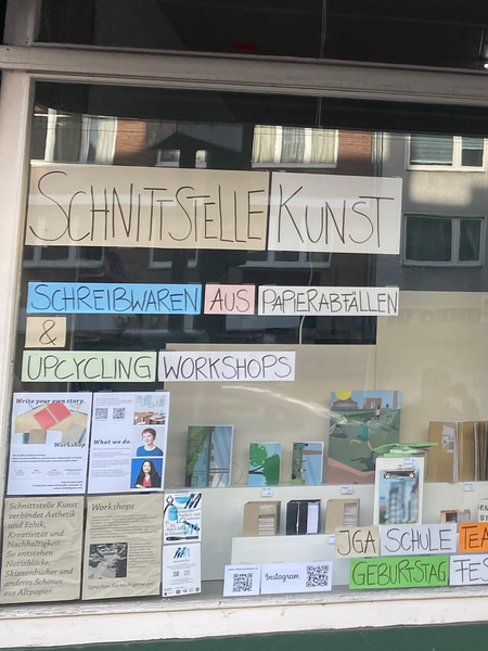 Das Atlier "Schnittstelle Kunst" in Düsseldorf von außen. In den Fenstern kleben viele bunte Papierzettel.