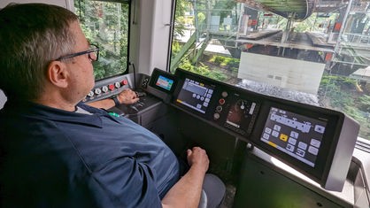 Mann sitzt im Cockpit einer Schwebebahn