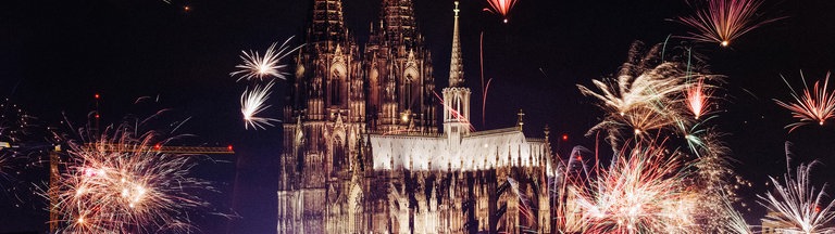 Der Kölner Dom an Silvester, es sind zahlreiche Feuerwerke zu sehen