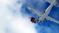 Ein Fallschirm-Tandem springt aus einem Flugzeug über Marl.