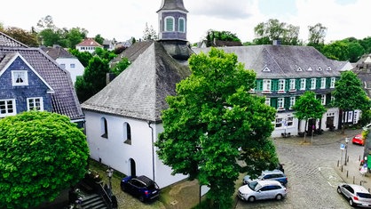 Eine Kirche umgeben von Häusern mit Schieferfassade