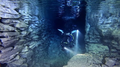 Zwei Taucher tauchen in einem mit Wasser gefüllten Bergwerk.