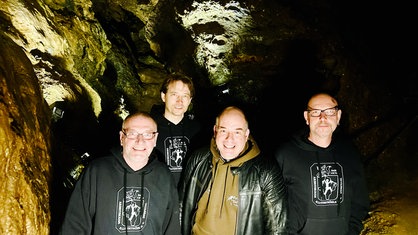 Vier Männer nebeneinander in einer Höhle