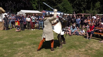 Zwei als Ritter verkleidete Männer kämpfen mit Schwertern gegeneinander