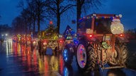 Mit Lichterketten und Weihnachtsdeko behangene Traktoren auf der Straße