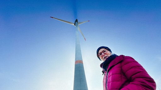 Ingrid Paprotté steht vor dem Windrad, auf das sie steigen wird.