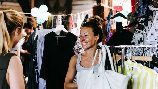 Zwei Frauen besuchen einen Trödelmarkt in einem alten Güterbahnhof.