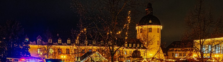 Weihnachtsmarktszenerie am Unteren Schloss in Siegen mit dem Schlossturm im Hintergrund.