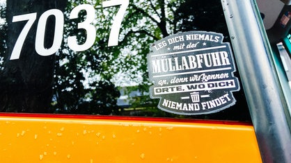 Ein Sticker an einem Müllauto mit dem Text: "Leg dich niemals mit der Müllabfuhr an, denn wir kennen Orte, wo dich niemand findet"