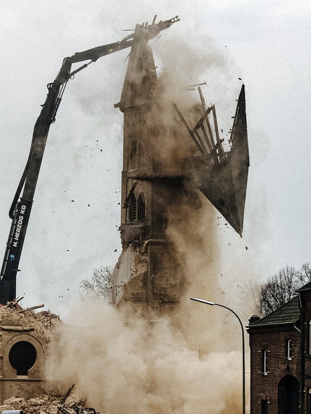 Der letzte Turm des Immerather Doms Sankt Lambertus wird abgerissen. Dabei fällt gerade die Turmspitze auf den Boden. Rechts davon leerstehende Wohnhäuser.