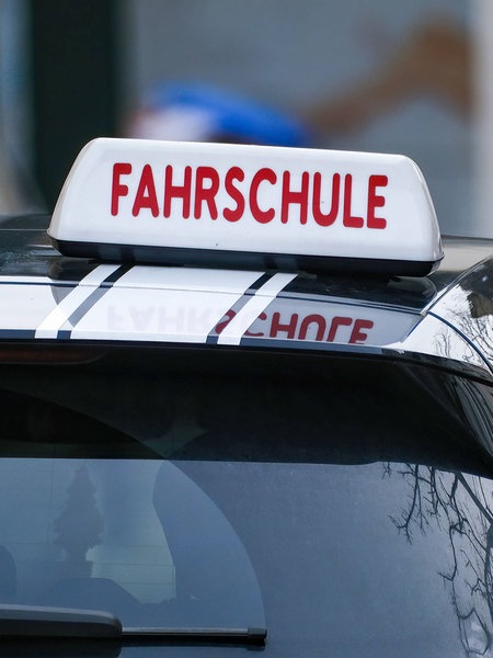 Ein Auto von hinten mit dem Schild "Fahrschule" auf dem Dach.