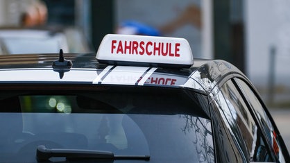 Ein Auto von hinten mit dem Schild "Fahrschule" auf dem Dach.