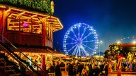 Der Weihnachtsmarkt Cranger Weihnachtszauber mit gut besuchten Ständen im Vordergrund und einem blau beleuchteten Riesenrad im Hintergrund.