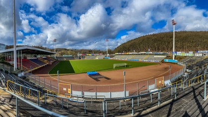 Die leren Tribünen und der Platz des Leimbachstadions in Siegen unter blauem Himmel