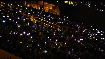 Auf den voll besetzten Tribünen des BVB-Stadions in Dortmund leuchten viele kleine Lichter.