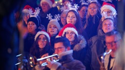 Junge Frauen mit Weihnachtsmützen und Schneeflocken auf dem Kopf singen bei "Loss mer Weihnachtsleeder singe" im Stadion in Köln