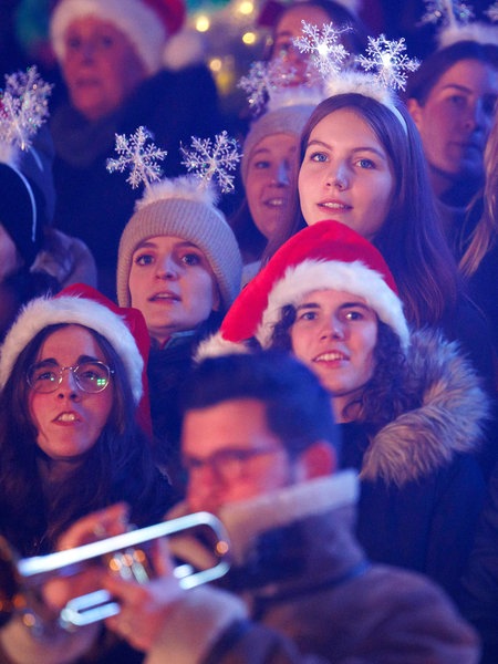 Junge Frauen mit Weihnachtsmützen und Schneeflocken auf dem Kopf singen bei "Loss mer Weihnachtsleeder singe" im Stadion in Köln