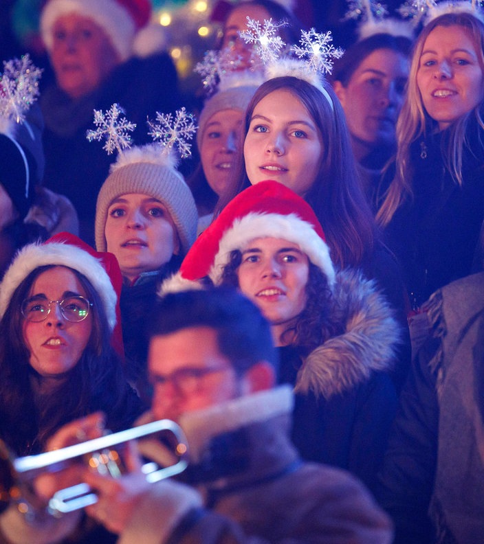 Junge Frauen mit Weihnachtsmützen und Schneeflocken auf dem Kopf singen bei "Loss mer Weihnachtsleeder singe" im Stadion in Köln