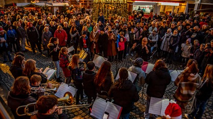 In Wesel stehen viele Menschen auf dem weihnachtlich geschmückten Platz vor dem Willibrordi-Dom, vor ihnen stehen Kinder, die Blasinstrumente spielen