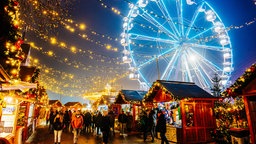 Blau leuchtendes Riesenrad auf dem Herner Weihnachtsmarkt hinter Weihnachtsmarktständen