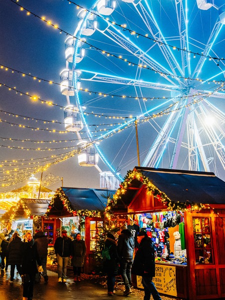 Blau leuchtendes Riesenrad auf dem Herner Weihnachtsmarkt hinter Weihnachtsmarktständen