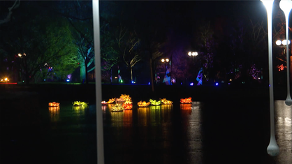 Auf einem See im Westfalenpark schwimmen kleine beleuchtete Schiffe.