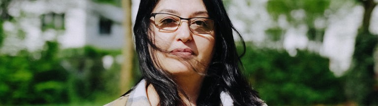 Aynur Satir, eine junge Frau mit schwarzen Haaren und einer eckigen Brille, schaut in die Kamera 