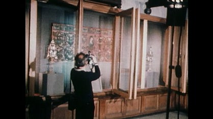Ein Mann steht vor geöffneten Holzvitrinen und macht Bilder mit Fotoapparat
