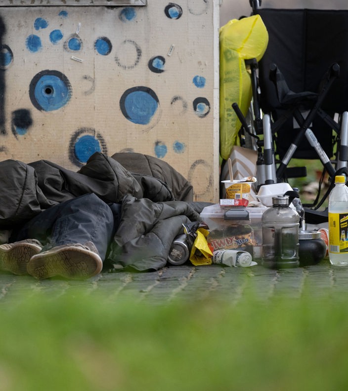 Eine Person liegt in einem Schlafsack auf einem Bürgersteig