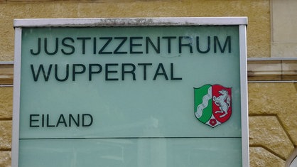 Schild, auf dem "Justizzentrum Wuppertal" steht, zusammen mit dem Wappen von NRW.