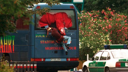 Archivbild: Ein verletzter Tourist springt aus dem Rückfenster des gekaperten Busses