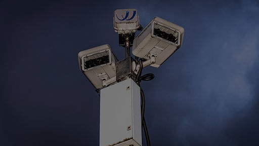 Eine Überwachungskamera vor einem dunklen Himmel.