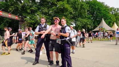 Eine Polizistin und ein Polizist lassen sich mit einem Besucher fotografieren