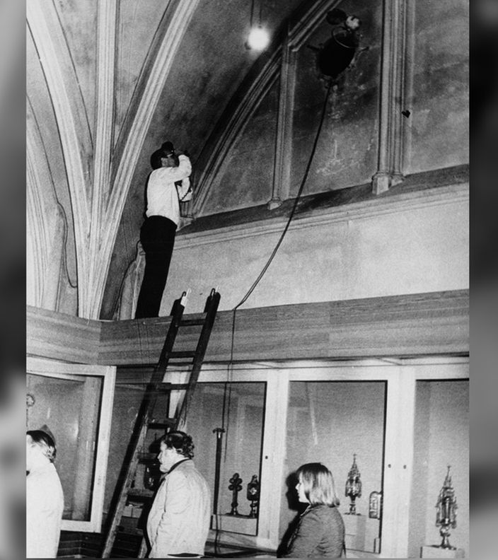 Schwarzweißfoto von 1975: Aus einem Loch oben in einer Wand hängt ein Seil, ein Mann macht ein Foto davon 