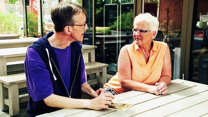 Die Verschickungskinder Udo Evers und Karin Kempf sitzen an einem Tisch und unterhalten sich.