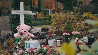 Ein Grab mit Stofftieren, Blumen und Andenken an die getötete Johanna K.