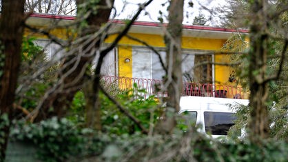 Durch Bäume ist das Wohnhaus des getöteten Unternehmer-Paars zu sehen