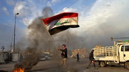 Irak, Baghdad: Ein Demonstrant schwenkt eine irakische Flagge. 
