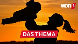 Der Schattenriss einer Mutter mit ihrem Baby im Sonnenuntergang auf einem Feldweg