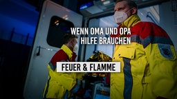 Zwei Sanitäter hinter RTW, Heck offen und Trage ragt raus