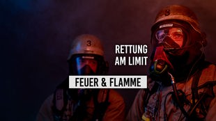 Zwei Feuerwehrleute mit Atemschutzmasken in dunkler Umgebung