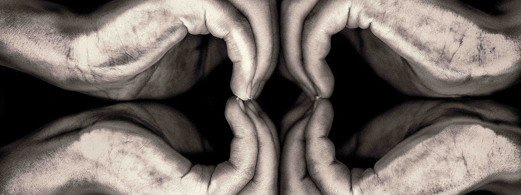 Zwei Hände formen Herzen vor schwarzem Hintergrund.