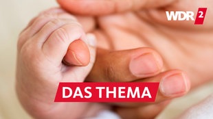 Hand eines Erwachsenen hält die Hand eines Babys