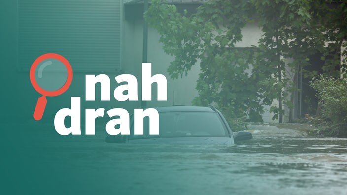 Ein Auto wird vom Hochwasser umspült. Das Wasser reicht fast bis zu den Seitenspiegeln.