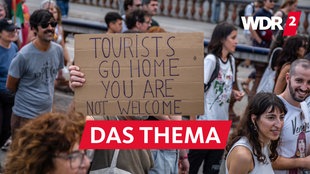 Demonstration gegen Massentourismus in Barcelona: Menschen halten ein Plakat mit der Aufschrift "Tourists go home - you are not welcome"