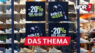 In einem Schaufenster mit Sneakern hängen Plakate zur ankündigung der "Black Week" mit Preisreduktionen um 20 Prozent 