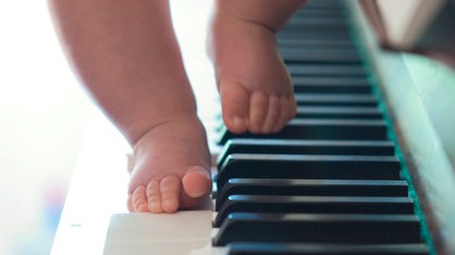 Babyfüße laufen über Klaviertasten.