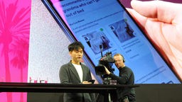 Jerry Yue, Gründer und Chef des US-Technologieunternehmens Brain Technologies, steht beim Mobile World Congress (MWC) auf einer Bühne und präsentiert einen Prototypen eines Künstliche-Intelligenz-Smartphones der Deutschen Telekom.